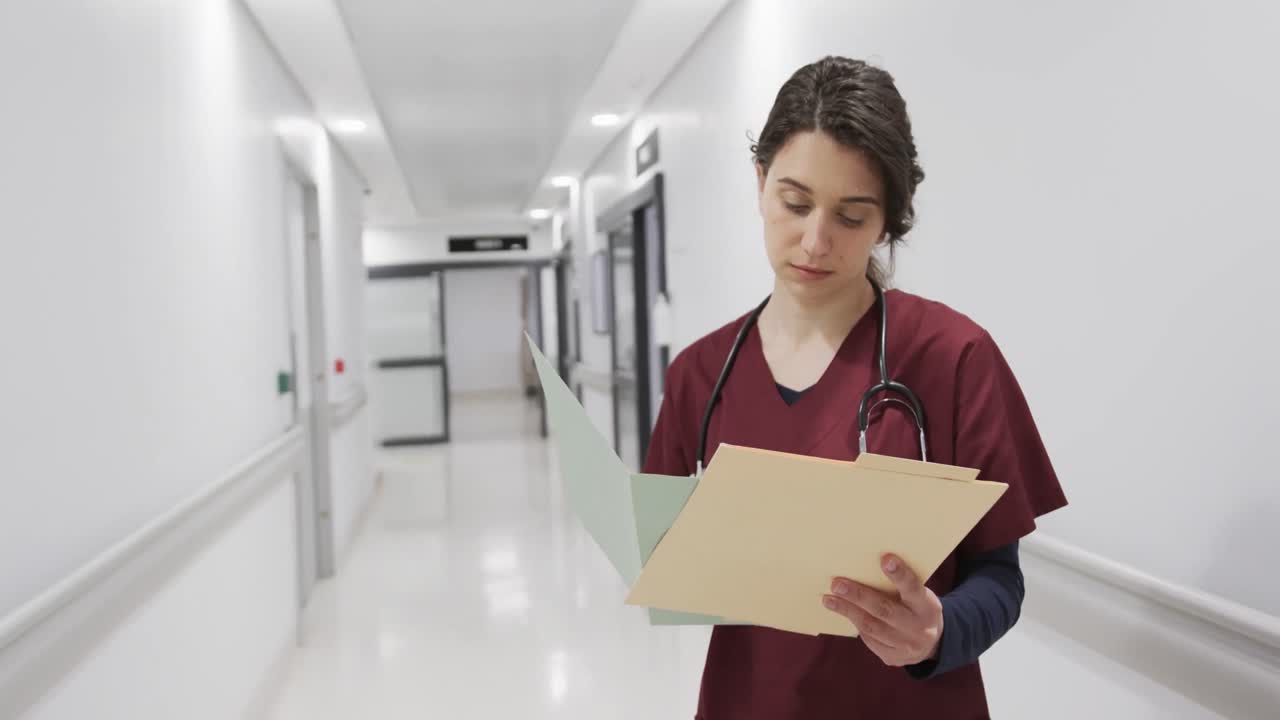 Ritratto di dottoressa caucasica felice che tiene documenti nel corridoio dell'ospedale, al rallentatore