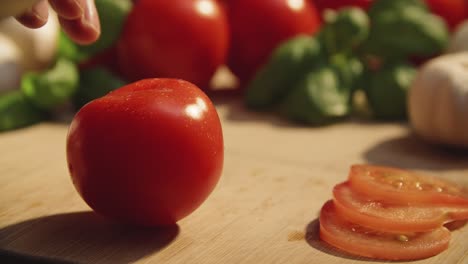 close up of chefs knife cutting tomato cleanly in two halfs along fingertips