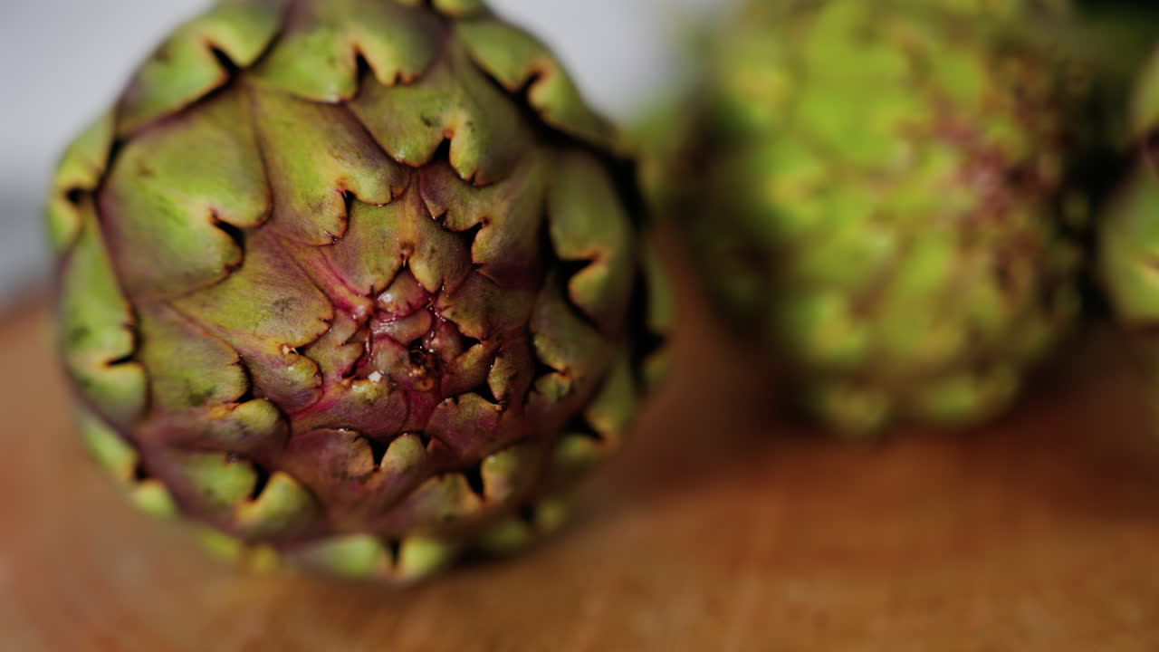 Close up of three artichokes on a wooden table