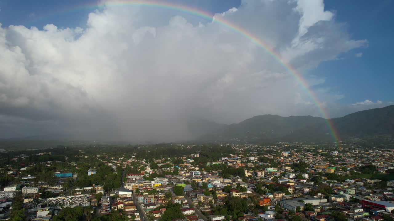 fotografía aérea de la ciudad de jarabacoa con un hermoso arco iris en el cielo