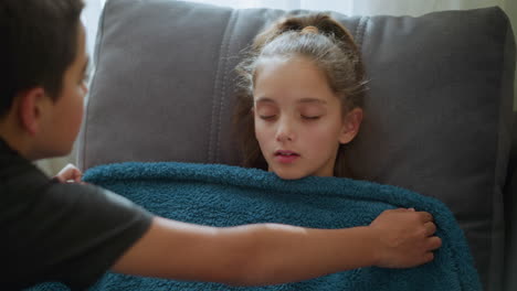 close-up of boy gently covering his sister who is sleeping peacefully, with soft light filtering through window, the sibling bond is visible as he ensures she's comfortable