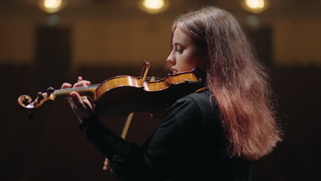 young female violin player is practicing to play violin in music hall portrait of female violinist