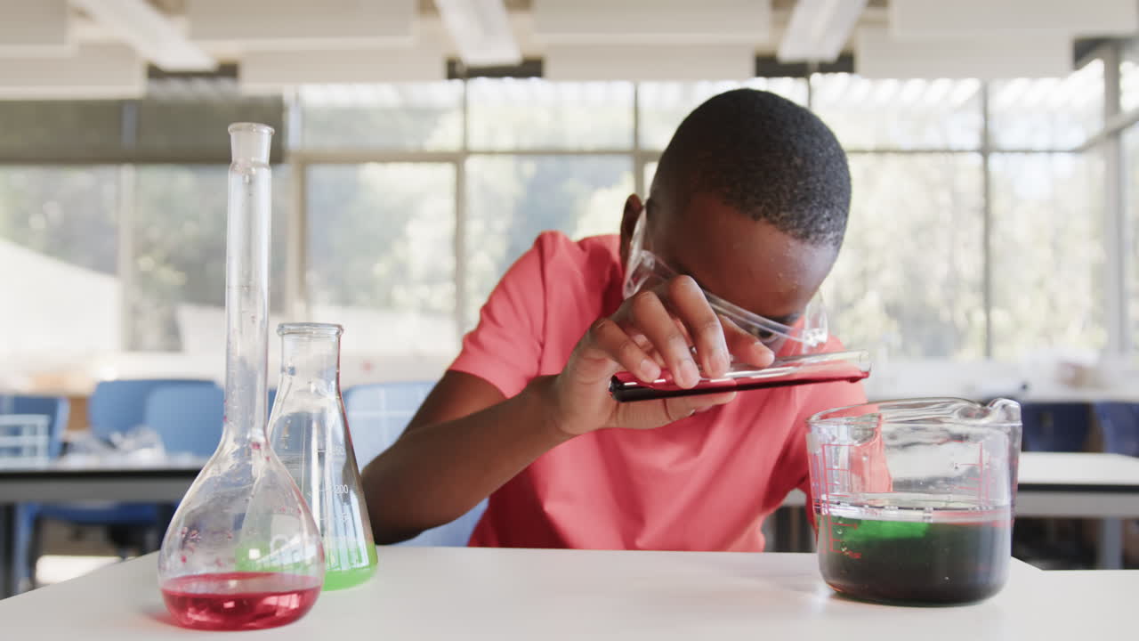 Conducting science experiment with test tubes and beakers, boy in school classroom