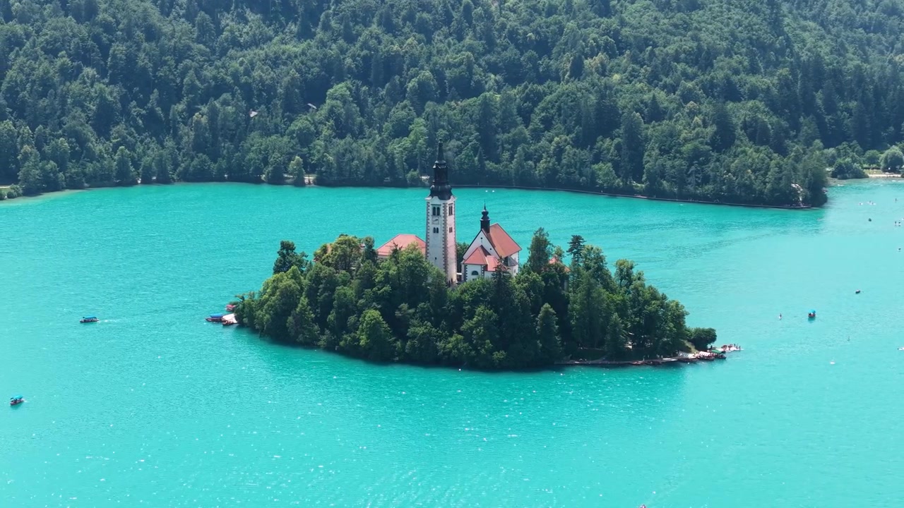 Ripresa con drone della Chiesa del Lago di Bled sull'isola in acque turchesi in una soleggiata giornata estiva, Slovenia