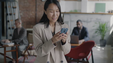 mujer usando un teléfono inteligente en una oficina moderna