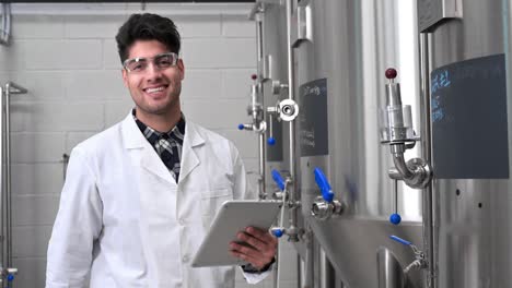 trabajador industrial tecnólogo con bata blanca y gafas de seguridad mirando la lista de comprobación y sonriendo a la cámara. trabajador de la planta comprobando la producción en la industria alimentaria. imágenes de alta calidad 4k