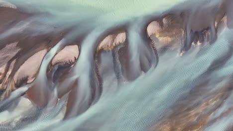 drone view looking down on a braided icelandic river flowing through iceland on it's journey from glacier to ocean