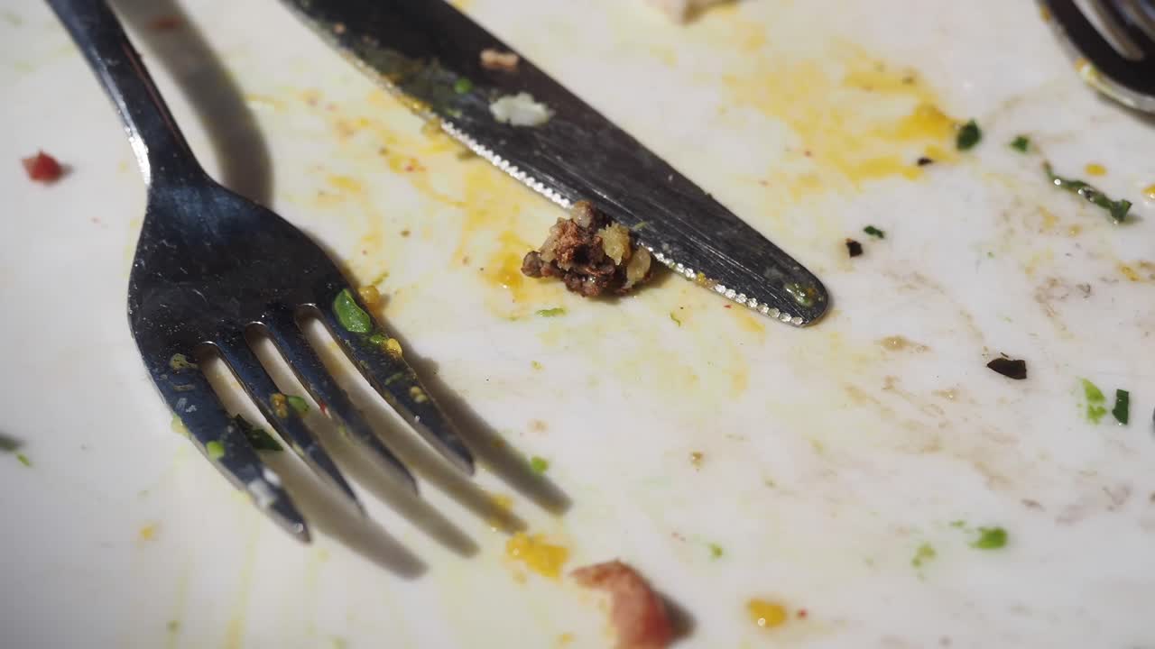 Close-up of a dirty plate with leftover food and cutlery