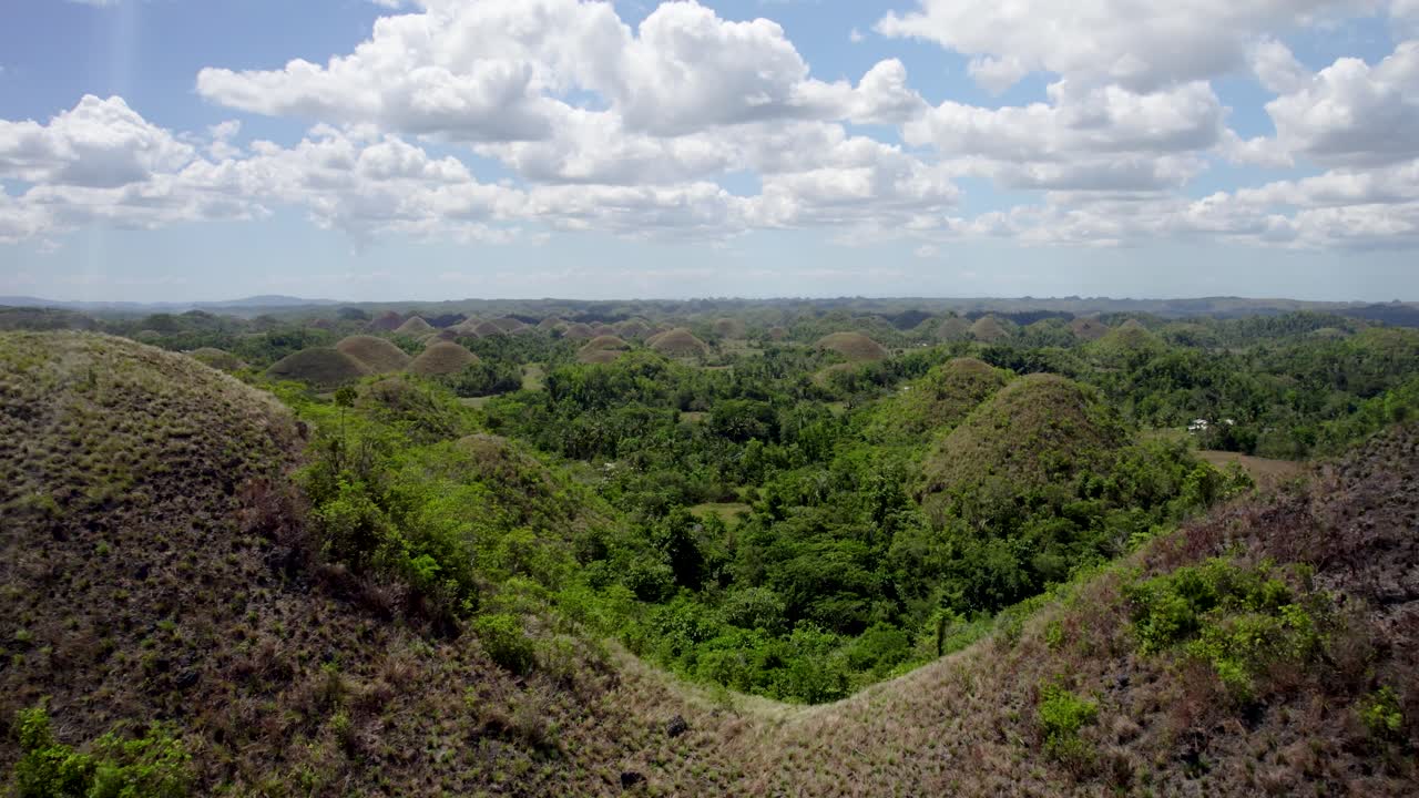 colinas de chocolate bajo un cielo brillante con nubes dispersas, vista aérea