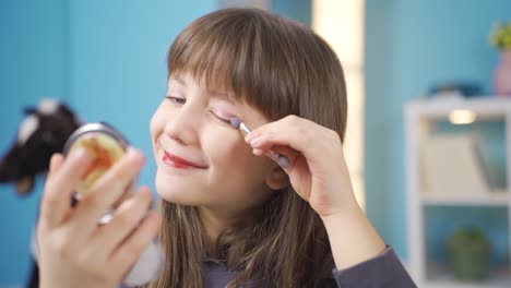 beautiful little girl learns to make up herself in the mirror.