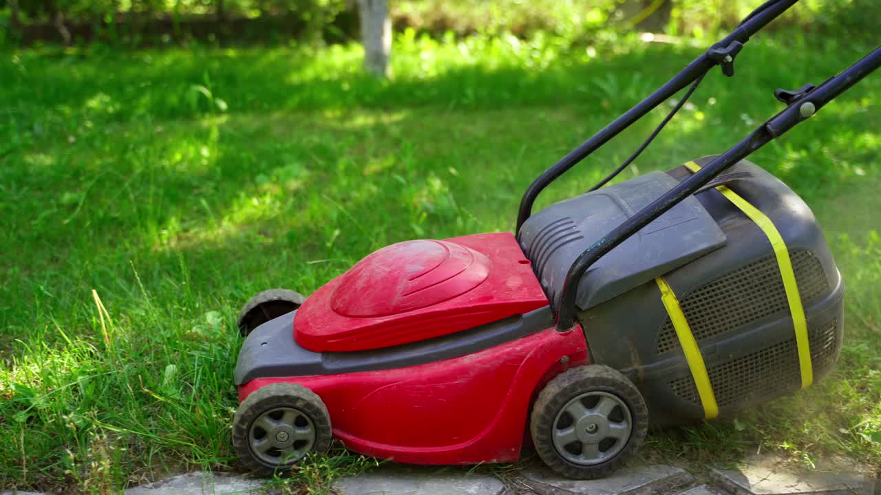 Garden mower equipment. Woman cutting green grass with corded lawn mower in the yard. Landscaping in the garden.