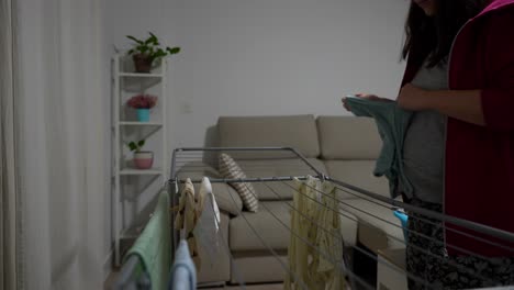 close up of clothesline as woman hangs baby clothes in living room at night