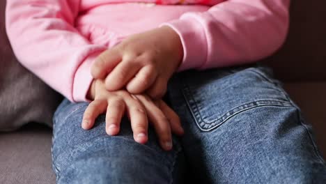 child sitting on sofa, touching legs