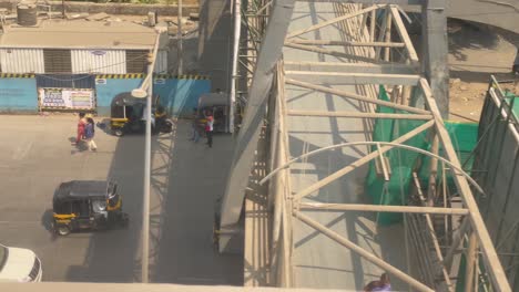 traffic on highway with tuk tuk tricycles and other transport vehicles driving at speed view from moving metro train in mumbai, india