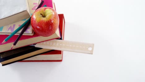 libros, lápices de color y manzana contra un fondo blanco