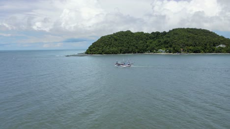 barco de pescadores rumbo al mar abierto con vista a la montaña en tailandia