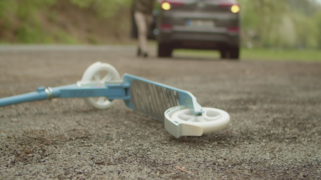 운전자는 문을 열고 바닥에 누워 있는 스쿠터를 보기 위해 달려갑니다