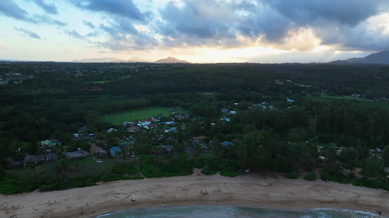 Establishing drone shot of a beach and village in Kauai, dusk in Hawaii, USA