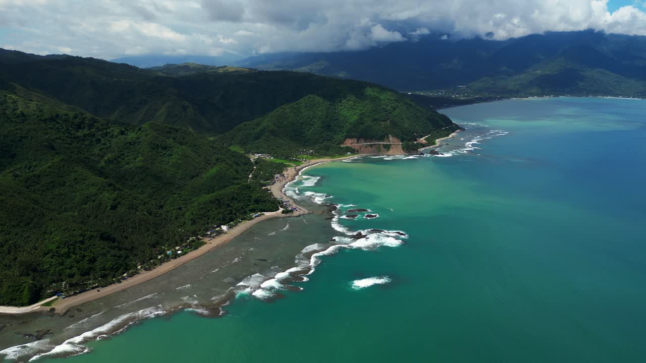 Slow forward elevated aerial shot over Dingalan, Aurora, gliding above turquoise waters, rugged shoreline, and lush green mountains that frame the dramatic coastal scenery