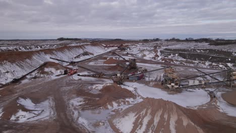 aerial view of industrial gravel pit mining, front end loader, machines, trucks - dolly shot