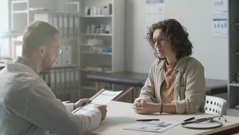 female patient discussing medical form with doctor in clinic