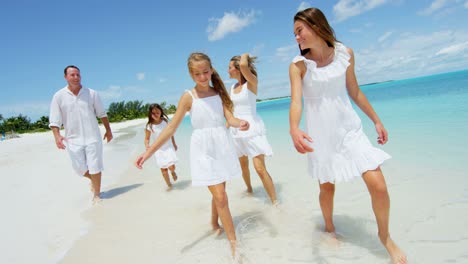 caucasian parents and their female children enjoying beach