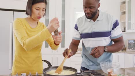 happy diverse couple cooking and preparing breakfast in kitchen