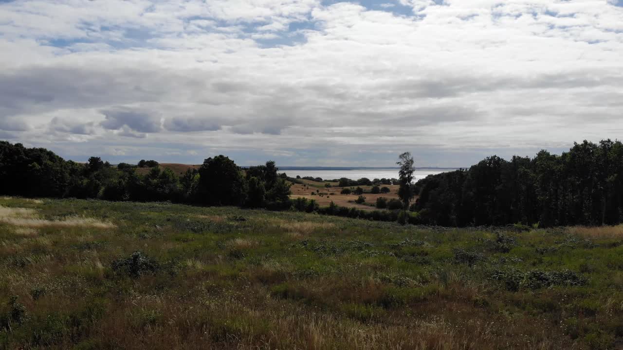 vista aérea de la costa de sejerã ̧bugten con colinas, campos y océano