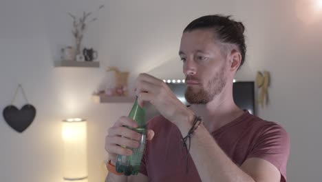 man is opening plastic water bottle and drinking from it, indoor household environment, slow motion, conquering thirst concept