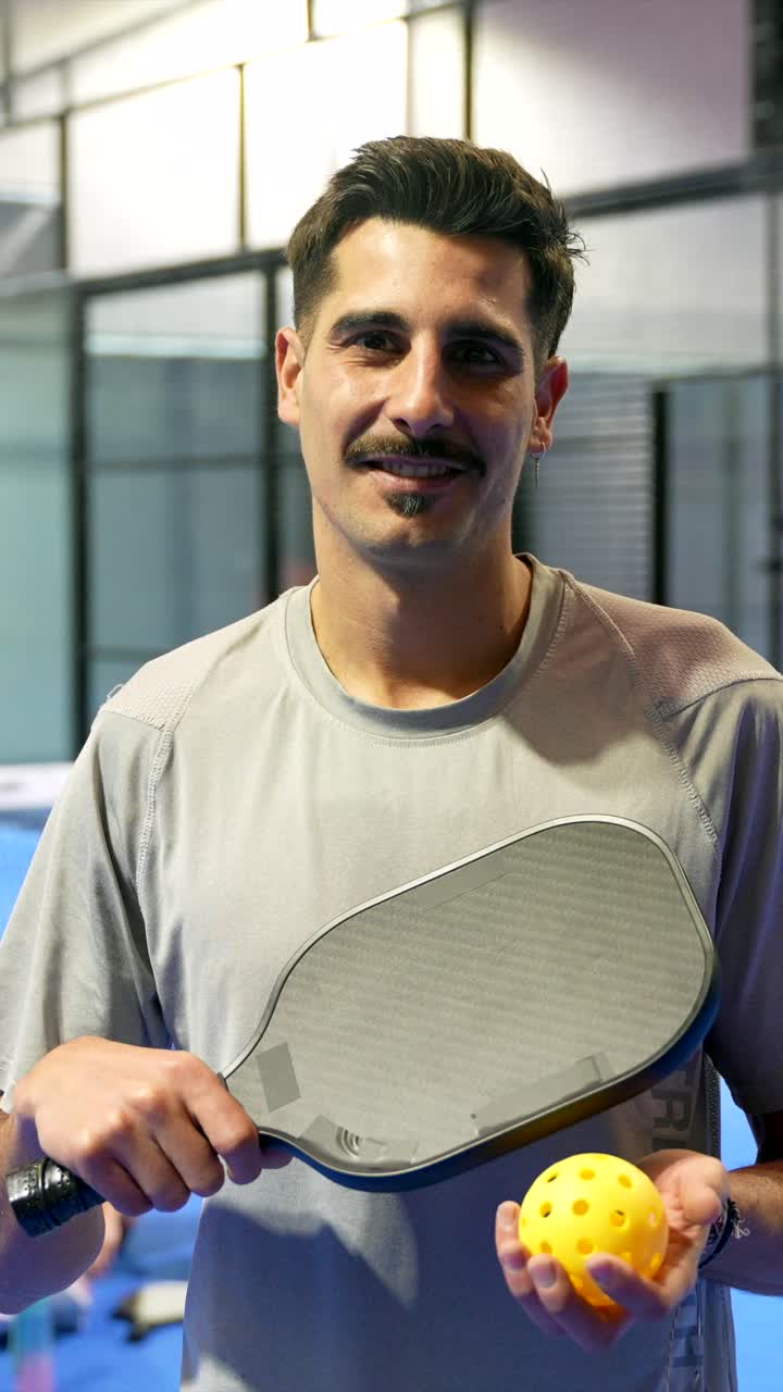 Man Smiling and Holding Pickleball Paddle and Ball on Court