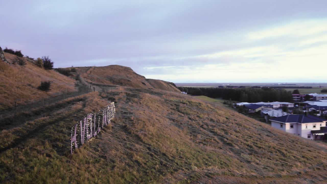 Hvollywood letters sign on hill in beautiful town hvolsv&ouml;llur, Iceland aerial during golden sunset