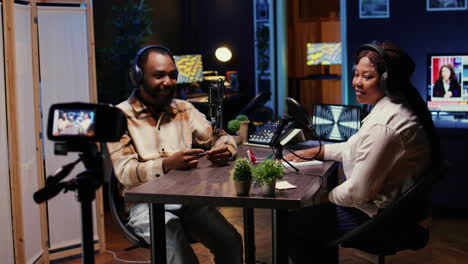 guest amused by talking show host telling jokes, recording with high tech equipment