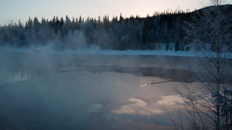 dreamy sunrise frosty morning rising mist from cold alpine woodland frozen lake, sweden