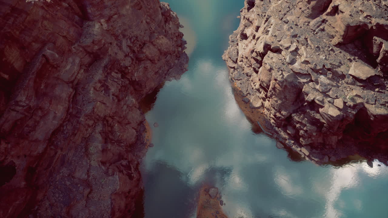 Rock formations meet calm water reflecting clouds in serene landscape