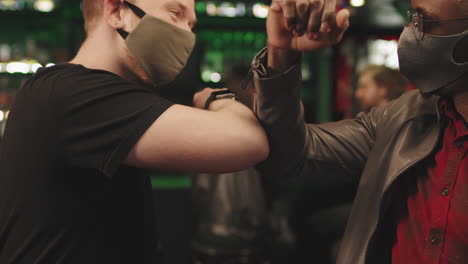 men in masks touching elbows in greeting