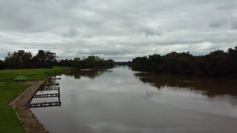 A-beautiful-river-reveal-shot-flying-between-2-trees-into-the-Vaal-River,-Free-State,-South-Africa