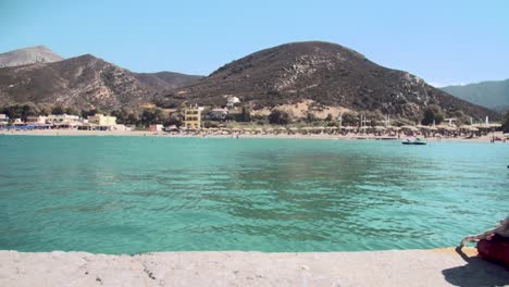 travelling shot over the bay of fodele beach with turquoise water revealing an bollard in crete, greece