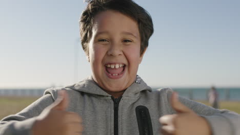 portrait of hispanic boy smiling cheerful celebrating thumbs up excited cheering enjoying sunny seaside park