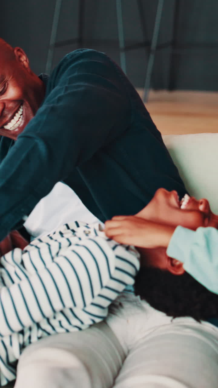 Padre felice che fa il solletico e gioca con i suoi figli sul divano