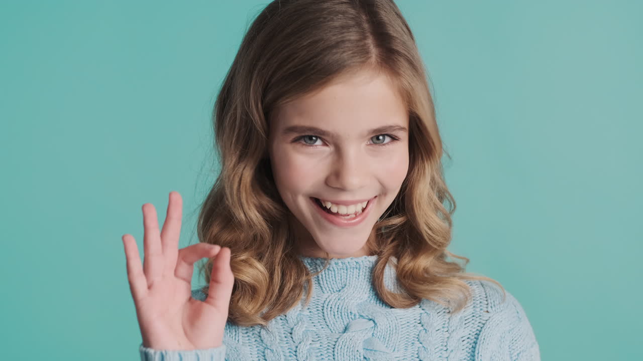 Teenage Caucasian girl nodding with thumbs up looking at the camera.