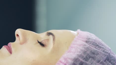 beautician in sterile gloves doing procedure plasmolifting injection into the patient's forehead in clinic. close-up