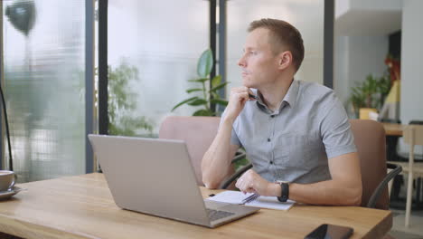 Man-college-student-using-laptop-computer-watching-distance-online-learning-seminar-class-remote-university-webinar-or-having-virtual-classroom-meeting-in-university-creative-space.