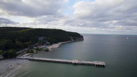 Orlowo-Pier-Und-öffentliche-Strandküste-An-Einem-Bewölkten-Sommertag-In-Gdingen,-Polen---Rückwärtsaufnahme-Des-Aufstands-Aus-Der-Luft