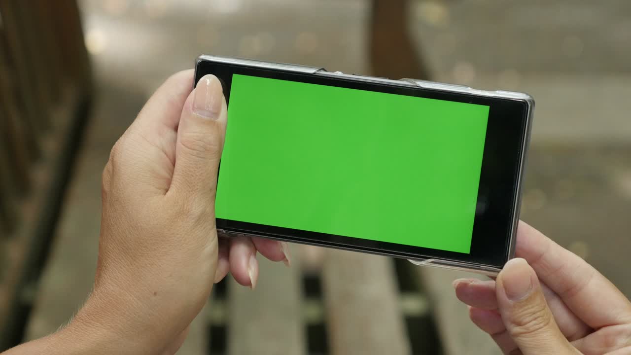 크로마 키를 들고 있는 벤치에 있는 여성 녹색 화면 전화