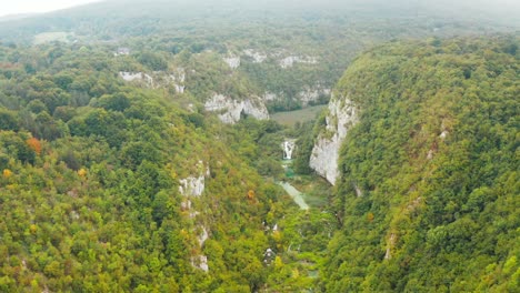 epic aerial drone shot flying over colorful mountainous forest canyon with rocky cliffs