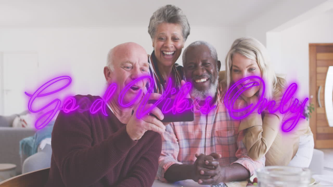Neon good vibes text against two senior diverse couple taking a selfie from smartphone at home