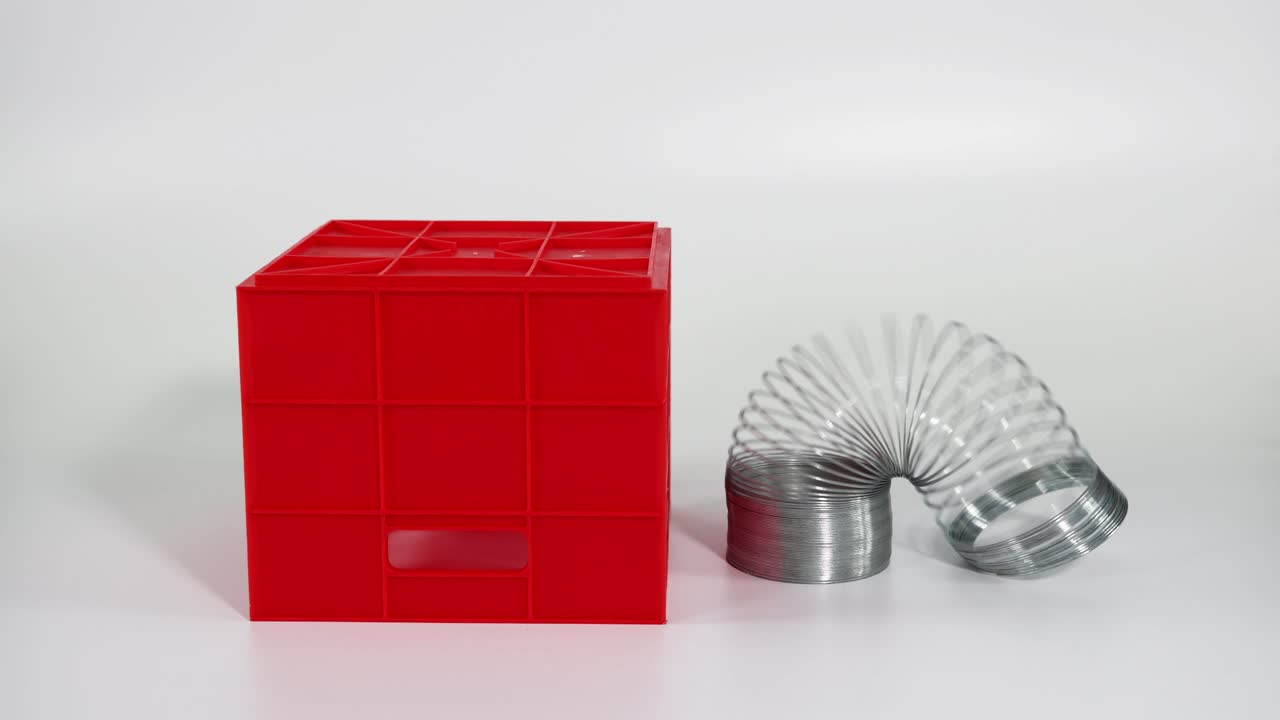 손은 빨간 블록 위에서 슬링키를 펼치고 있습니다.