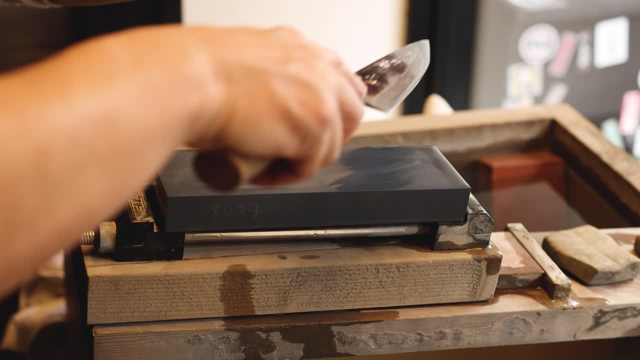 Hands skillfully sharpening a knife on a stone