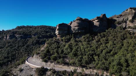 Winding-road-through-the-scenic-Tavertet-region-with-rocky-cliffs-and-lush-greenery-under-a-clear-sky