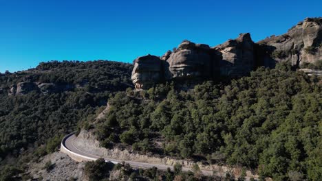 winding road through the scenic tavertet region with rocky cliffs and lush greenery under a clear sky